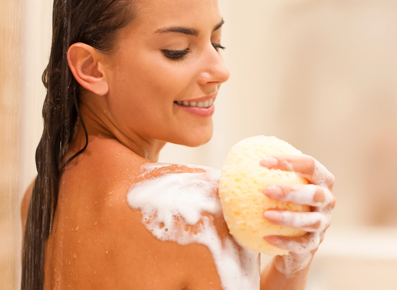 Donna sotto una cascata naturale immersa nella freschezza dell'acqua, simbolo di pulizia profonda e rigenerazione ispirata ai detergenti corpo di Rugiada Mediterranea