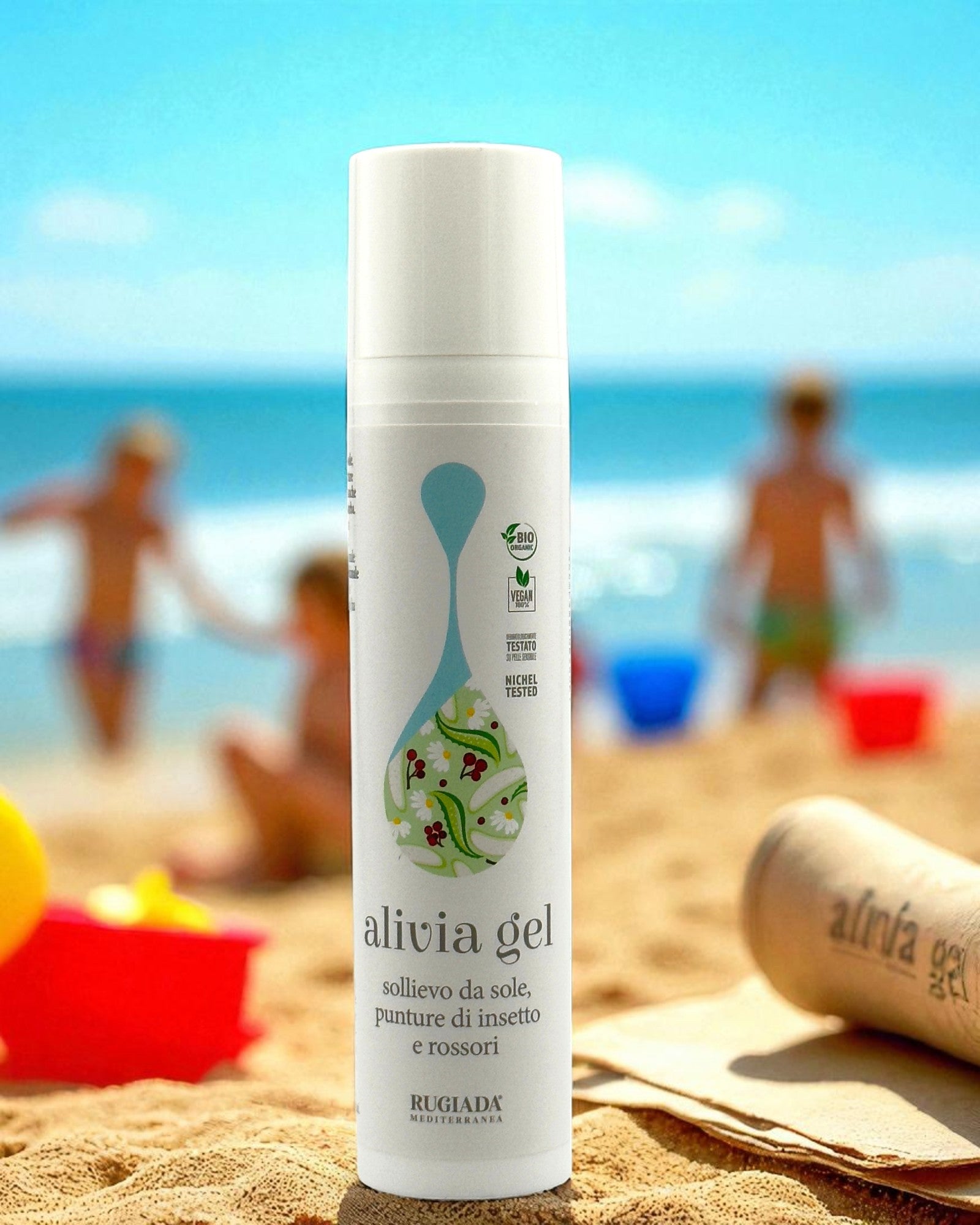 Flacone di Alivia Gel sulla sabbia, con bambini che giocano in spiaggia sullo sfondo.